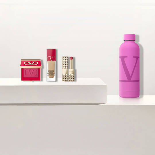 Valentino-Schonheitsprodukte und eine rosa Wasserflasche mit dem "V"-Logo.