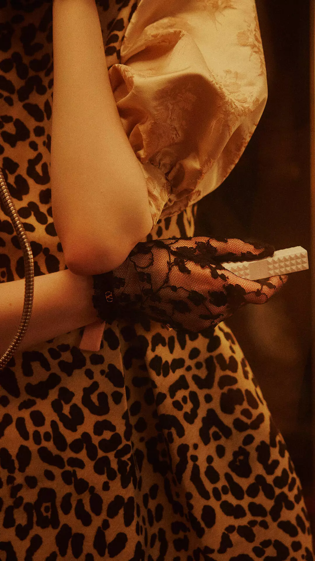 Eine Frau mit schwarzen Spitzenhandschuhen, die SPIKE VALENTINO IVORY halt, druckt die Tasten eines Vintage-Telefons.