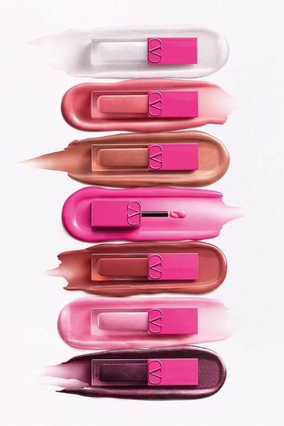An array of lip products in various shades, including shades of pink, nude, and berry, displayed on a light background with swatches beneath each product.